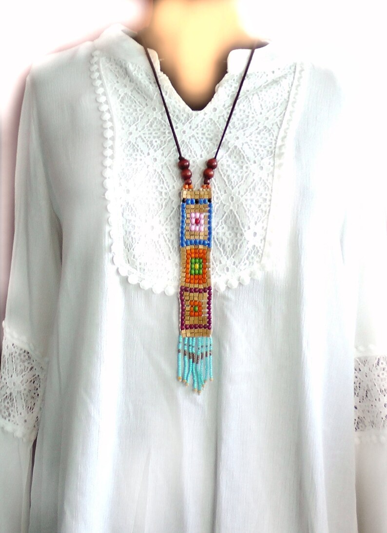 May include: A long beaded necklace with a colorful geometric pattern and a turquoise fringe. The necklace is made of small, colorful beads and is strung on a brown cord.