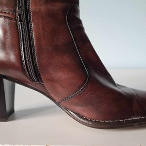 May include: A pair of brown leather heeled boots with a zip on the inside of the ankle.