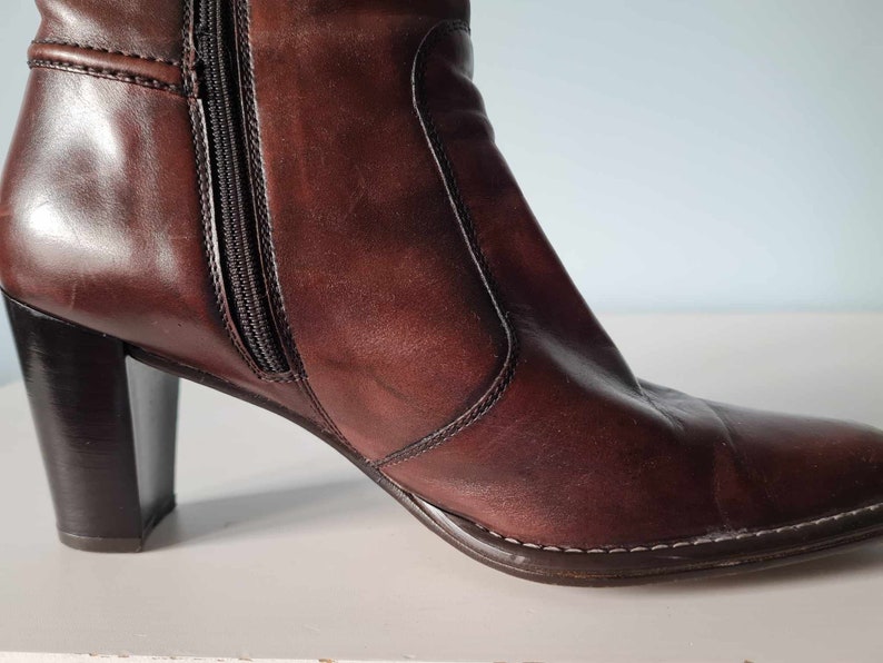 May include: A pair of brown leather heeled boots with a zip on the inside of the ankle.