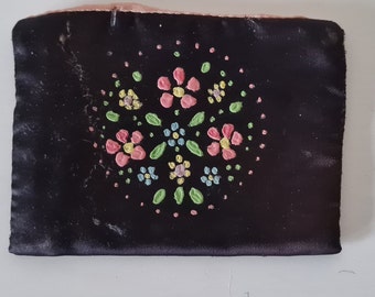 May include: A black satin pouch with a pink, green, and yellow floral design embroidered on the front.