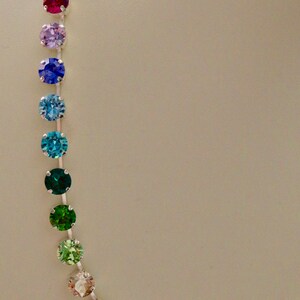 Puede incluir: Un collar de cadena de plata con un arco&iacute;ris de cristales redondos y facetados. Los cristales son en tonos de rojo, rosa, morado, azul, verde y transparente.