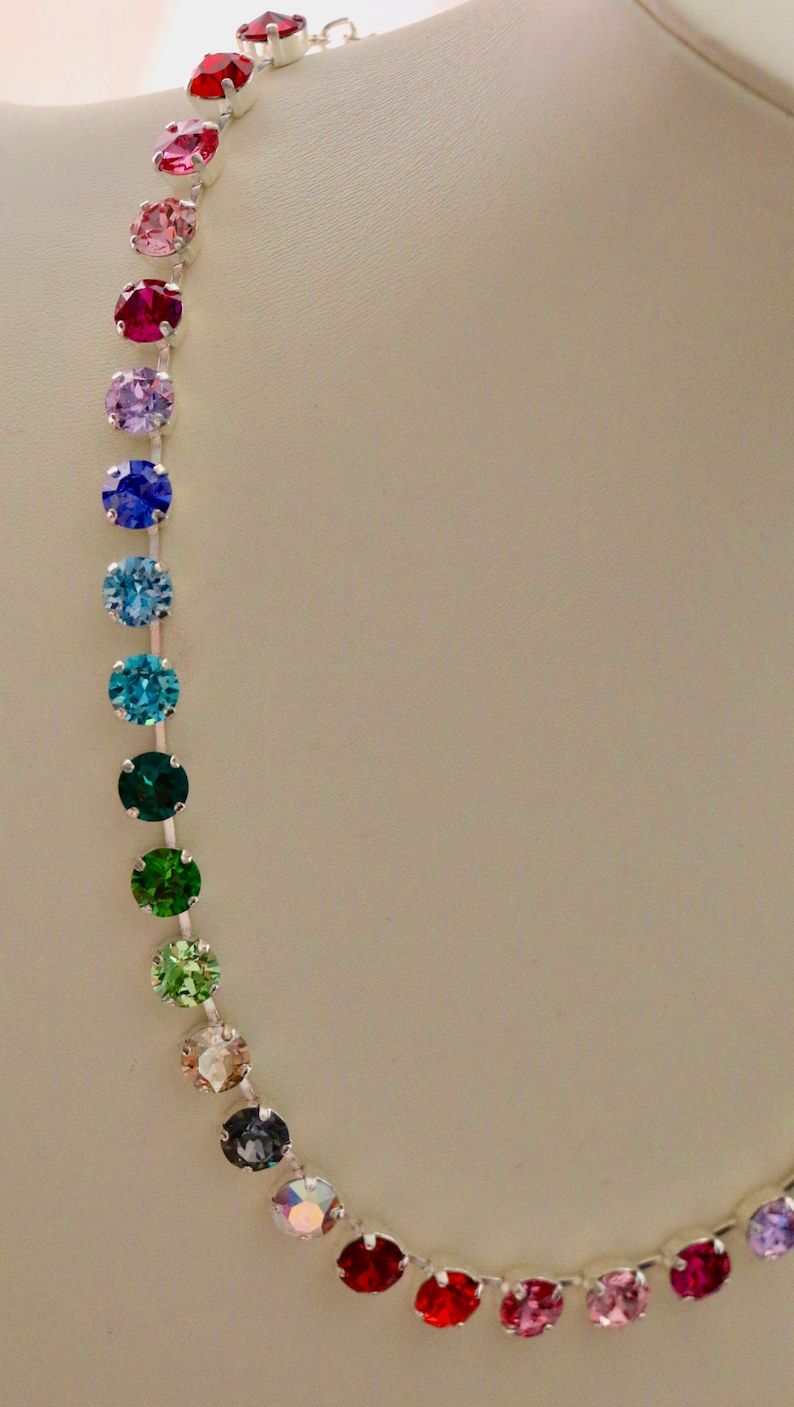 Puede incluir: Un collar de cadena de plata con un arco&iacute;ris de cristales redondos y facetados. Los cristales son en tonos de rojo, rosa, morado, azul, verde y transparente.