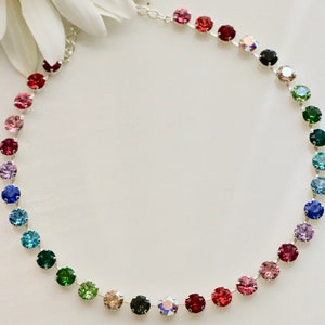 Puede incluir: Un collar de cadena plateada con un arco&iacute;ris de cristales redondos de colores. Los cristales est&aacute;n dispuestos en un degradado de rosa a verde.