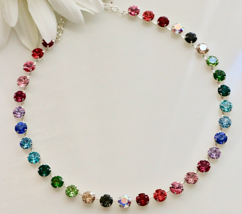 Puede incluir: Un collar de cadena plateada con un arco&iacute;ris de cristales redondos de colores. Los cristales est&aacute;n dispuestos en un degradado de rosa a verde.