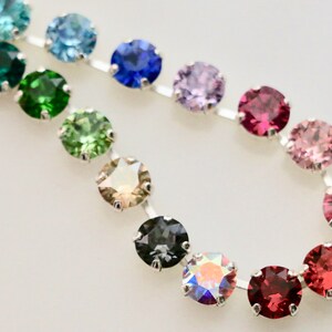 Puede incluir: Una cadena de plata con piedras preciosas redondas y facetadas en varios colores, incluyendo azul, verde, marr&oacute;n, gris, morado, rosa y rojo.