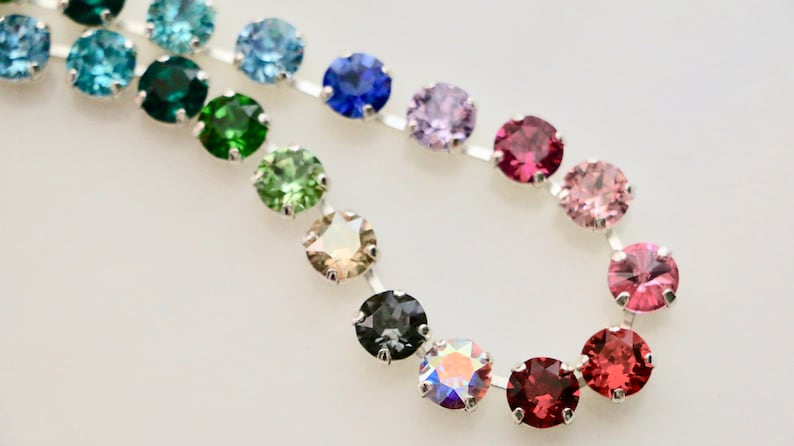 Puede incluir: Una cadena de plata con piedras preciosas redondas y facetadas en varios colores, incluyendo azul, verde, marr&oacute;n, gris, morado, rosa y rojo.