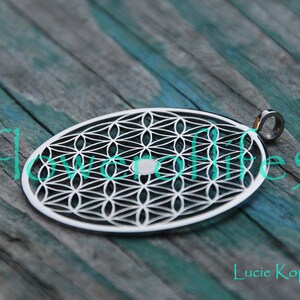 May include: Silver pendant featuring a geometric flower of life design. The pendant is oval shaped and has a small loop at the top for attaching a chain.