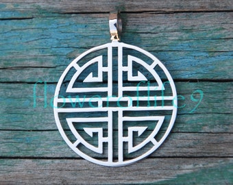 May include: Silver pendant with a circular design featuring a geometric pattern. The pendant has a gold bail and is on a wooden background.