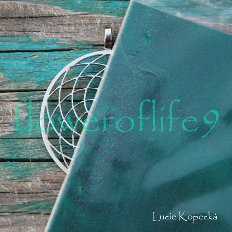 May include: A silver metal pendant with a circular geometric design. The pendant is partially obscured by a teal blue background with the text "floweroflife9" and "Lucie Kopeck&aacute;" in white.