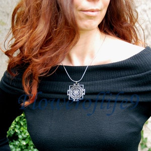 K&ouml;nnte beinhalten: Eine Frau tr&auml;gt einen schwarzen, schulterfreien Pullover mit einer silbernen Halskette mit einem geometrischen Anh&auml;nger.