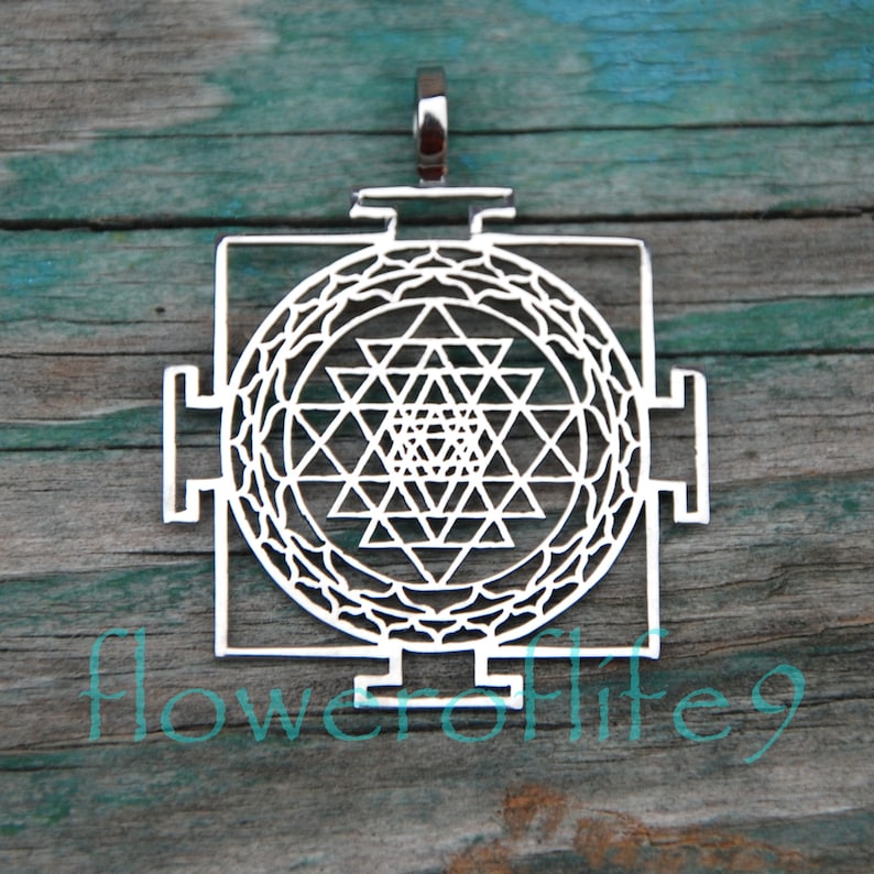 May include: Silver pendant featuring a Sri Yantra, a sacred geometric symbol in Hinduism. The pendant is intricately designed with a central star and multiple triangles.