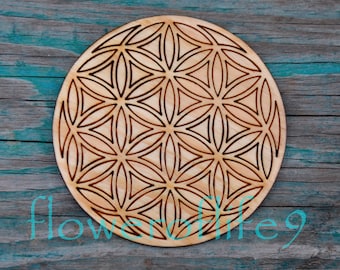 Könnte beinhalten: Ein Holz-Untersetzer mit einem lasergravierten geometrischen Muster, bekannt als Blume des Lebens, in hellbrauner Farbe.