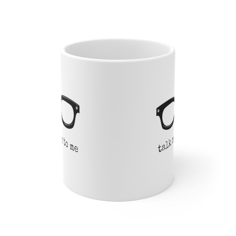 Op de afbeelding: Witte keramische mok met een zwarte brilafbeelding aan beide zijden. De tekst "talk to me" staat aan de ene kant en "talk nerdy" aan de andere kant, in een lettertype in typemachinestijl.