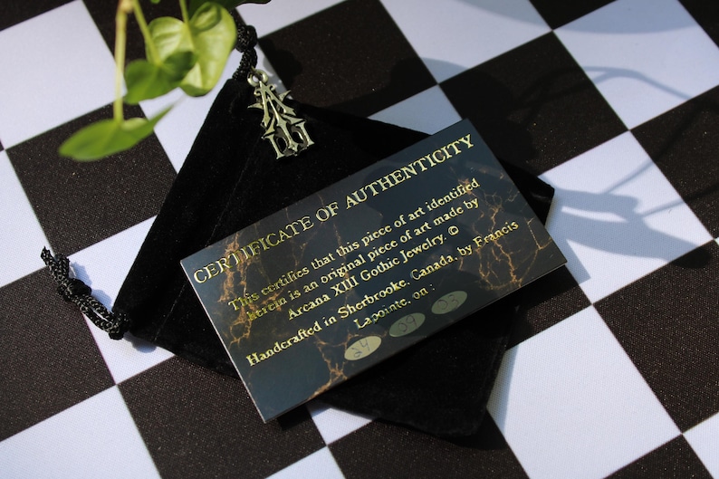 May include: A black velvet pouch with a gold certificate of authenticity inside. The certificate reads "This certifies that this piece of art identified herein is an original piece of art made by Arcana XIII Gothic Jewelry. Handcrafted in Sherbrooke, Canada, by Francis Lapointe, on:"