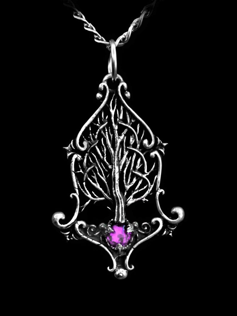 K&ouml;nnte beinhalten: Eine silberne Halskette mit einem detaillierten Baumdesign und einem violetten Edelstein an der Basis. Der Anh&auml;nger ist an einer silbernen Kette befestigt.