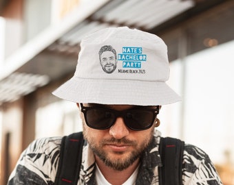May include: White bucket hat with a blue and white graphic that says "Nate's Bachelor Party Miami Beach 2023".