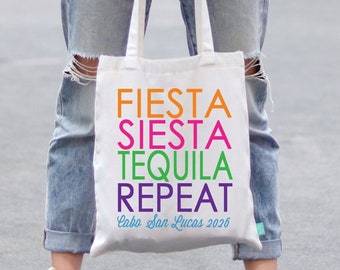 Peut inclure: Un sac fourre-tout blanc avec le texte "FIESTA SIESTA TEQUILA REPEAT Cabo San Lucas 2026" en lettres colorées.