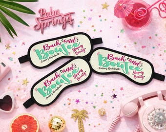 Puede incluir: Tres antifaces para dormir de color crema con borde negro y bandas elásticas. Cada antifaz presenta el texto "Bach and Boujee" en letra cursiva turquesa y rosa, "Connie's Bachelorette" en negro y "Sleeping Beauty" en rosa.