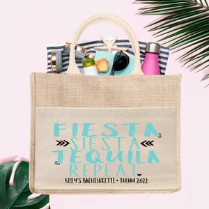 May include: A beige burlap tote bag with a white pocket featuring the text "FIESTA SIESTA TEQUILA REPEAT" in turquoise blue. The text "KELLY'S BACHELORETTE - TULUM 2022" is printed below in black.