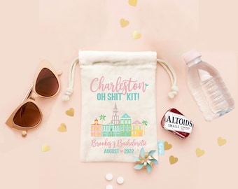 Puede incluir: Una bolsa de color crema con cordón impresa con el texto Charleston OH SHIT KIT! Brookes's Bachelorette AUGUST 2022 y un gráfico colorido del horizonte de la ciudad, acompañada de gafas de sol marrones, una botella de agua, mentas Altoids y un pequeño molinillo.