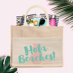 Op de afbeelding: Een beige jute draagtas met een wit canvas vak met de tekst "Hola Beaches!" in turquoise met een roze ananas afbeelding. De tekst "SARAH + RICH" en "RIVIERA MAYA, MEXICO" is in zwart onder de afbeelding gedrukt.