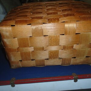Puede incluir: Una cesta de mimbre de madera de color marr&oacute;n claro. La cesta est&aacute; hecha de finas tiras de madera que se tejen juntas para crear un recipiente resistente y duradero.