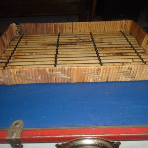 May include: A rectangular woven tray made of natural brown bamboo with a black woven design. The tray is empty and sitting on a blue surface.