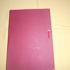 May include: A burgundy folder with a red ribbon closure.