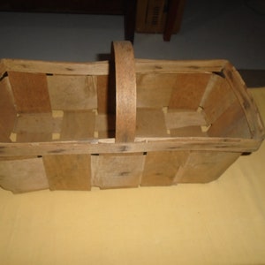 K&ouml;nnte beinhalten: Ein Korb aus Holz mit geflochtenem Muster und einem einzelnen Griff. Der Korb ist leer und hat eine nat&uuml;rliche Holzoptik.