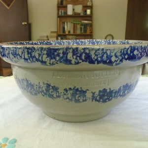May include: A beige ceramic mixing bowl with a wide rim and a rounded base. The bowl features a blue sponge-painted pattern around the top and middle sections. Embossed text on the side reads Beaumont Pottery York Maine in a rectangular frame.