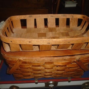Puede incluir: Una cesta de madera con un dise&ntilde;o tejido. La cesta est&aacute; hecha de madera natural y tiene una forma rectangular. Tiene dos asas a los lados.
