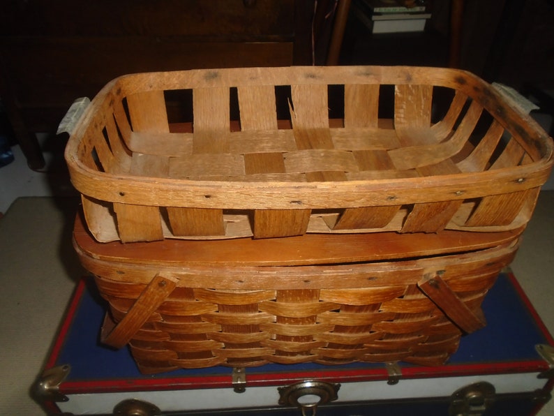Puede incluir: Una cesta de madera con un dise&ntilde;o tejido. La cesta est&aacute; hecha de madera natural y tiene una forma rectangular. Tiene dos asas a los lados.