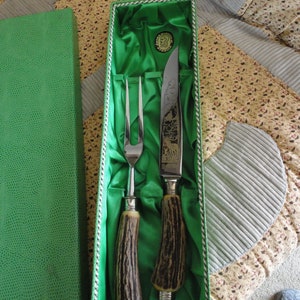 May include: A set of a carving knife and fork with stag horn handles in a green velvet lined box.