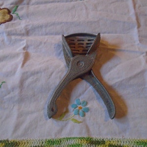 May include: A vintage silver-colored citrus juicer with a criss-cross design. The juicer is open and ready to use.