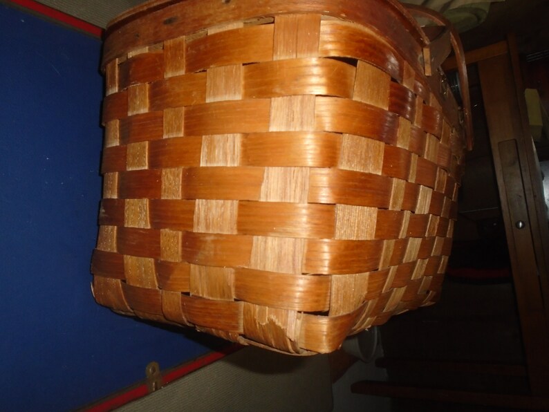 Puede incluir: Una cesta de mimbre tejida marr&oacute;n con un asa de madera.