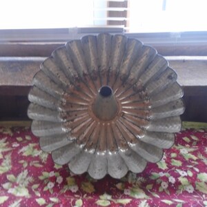 May include: A vintage metal cake pan with a fluted edge and a central hole. The pan is silver with a copper-colored interior.