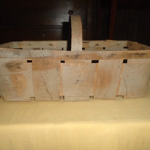 K&ouml;nnte beinhalten: Ein Vintage-Korb aus Holz mit einem Griff. Der Korb ist aus geflochtenen Holzlatten gefertigt und hat eine rechteckige Form. Der Korb ist verwittert und hat ein rustikales Aussehen.