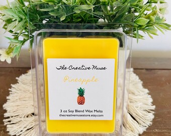 May include: A yellow pineapple-scented soy wax melt in a clear plastic container. The label reads "The Creative Muse" and "Pineapple" with a pineapple illustration. The product is 3 oz.