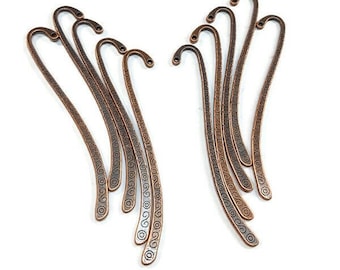 May include: Ten copper bookmark pendants with a swirl design. The bookmarks are about 2 inches long and have a hook at the top.