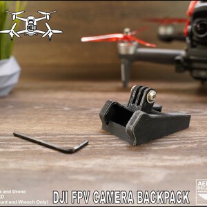 May include: A black 3D printed GoPro camera mount for a DJI FPV drone. The mount is designed to attach to the drone's camera backpack. The text "DJI FPV CAMERA BACKPACK" is visible in the image.