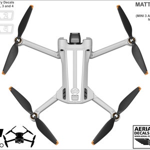 K&ouml;nnte beinhalten: Matte wei&szlig;e Aufkleber f&uuml;r eine DJI Mini 3 Pro Drohne. Die Aufkleber beinhalten nummerierte Batterieaufkleber und wei&szlig;e Streifen f&uuml;r den Drohnenk&ouml;rper. Die Drohne ist nicht im Lieferumfang enthalten.