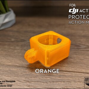 May include: Orange 3D printed protector for a DJI Action 2 camera. The protector is designed to mount to the camera's action mount.  FOR: DJI ACTION 2 PROTECTOR ACTION MOUNT