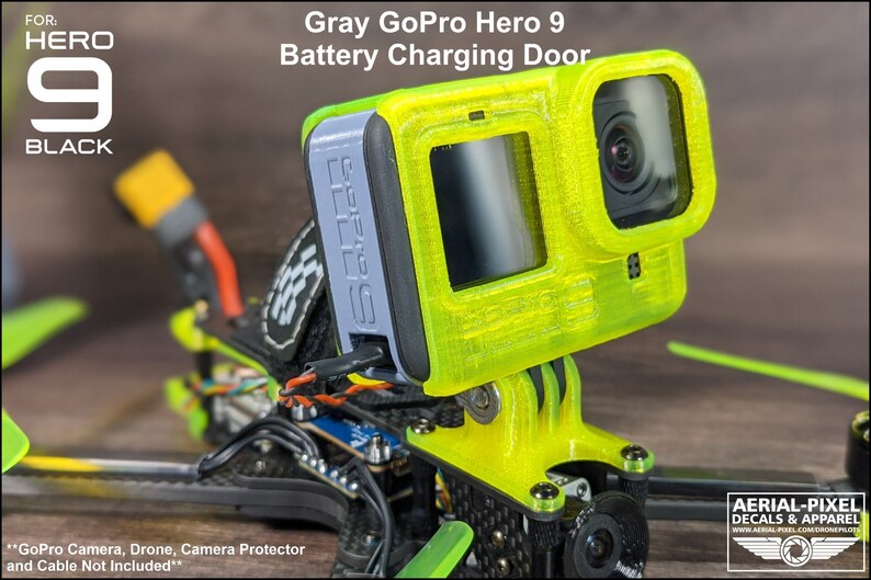 May include: Gray 3D printed GoPro Hero 9 battery charging door. The door is attached to a drone with a yellow and black frame. The text "GoPro Camera, Drone, Camera Protector and Cable Not Included" is visible at the bottom of the image.