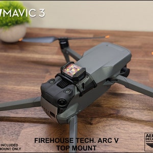 K&ouml;nnte beinhalten: Ein 3D-gedruckter Halter f&uuml;r ein Stroboskoplicht, das f&uuml;r die Montage auf einem DJI Mavic 3 Drohnen passt. Der Halter ist schwarz und hat eine strukturierte Oberfl&auml;che. Der Text "FIREHOUSE TECH. ARC V TOP MOUNT" ist auf dem Halter aufgedruckt.