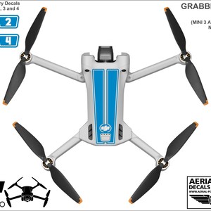 K&ouml;nnte beinhalten: Ein Satz blauer und wei&szlig;er Aufkleber f&uuml;r eine DJI Mini 3 Pro Drohne. Die Aufkleber haben ein blaues Rennstreifendesign mit wei&szlig;en Akzenten. Das Set enth&auml;lt Aufkleber f&uuml;r den Drohnenk&ouml;rper und den Akku. Die Aufkleber sind mit "Grabber Blue Decals" und "Mini 3 und Batterien nicht im Lieferumfang enthalten" beschriftet.