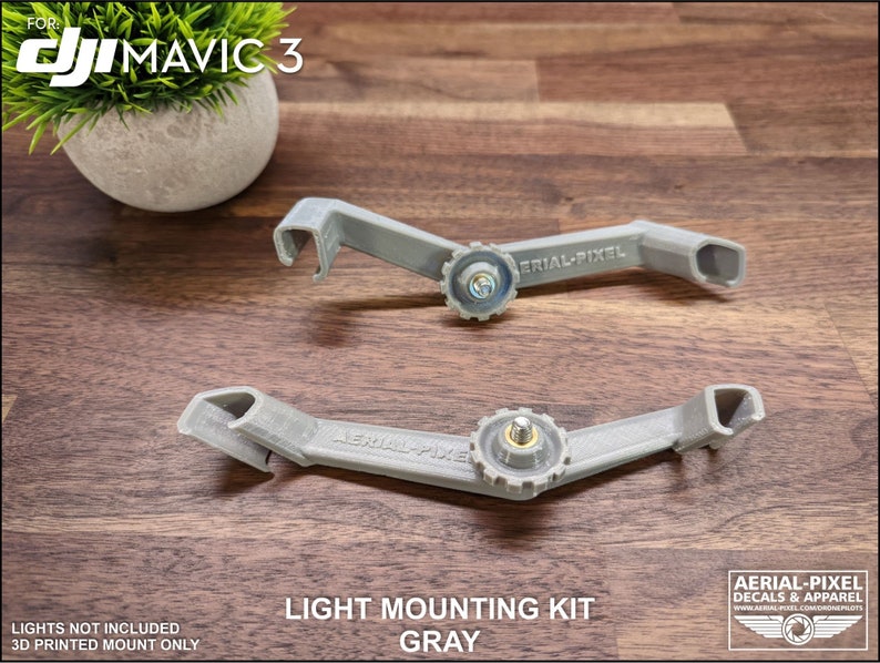 K&ouml;nnte beinhalten: Zwei graue Lichtmontages&auml;tze f&uuml;r DJI Mavic 3 Drohnen. Die S&auml;tze sind 3D-gedruckt und verf&uuml;gen &uuml;ber einen zentralen Schraubmechanismus und den Text "AERIAL-PIXEL". Das Bild enth&auml;lt auch den Text "LIGHT MOUNTING KIT GRAY".