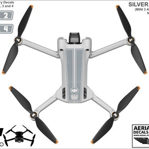 K&ouml;nnte beinhalten: Silberne Aufkleber f&uuml;r eine DJI Mini 3 Pro Drohne. Die Aufkleber sind so konzipiert, dass sie auf den Rumpf und die Propeller der Drohne passen. Die Aufkleber sind von 1 bis 4 nummeriert. Das Bild zeigt die Aufkleber, die auf die Drohne aufgebracht wurden.