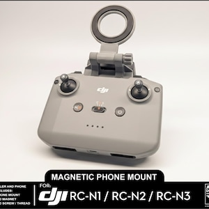 May include: A gray magnetic phone mount for DJI RC-N1, RC-N2, and RC-N3 remote controllers. The mount features a circular phone holder and is designed to attach to the controller. The image includes text indicating the mount's compatibility and included components.