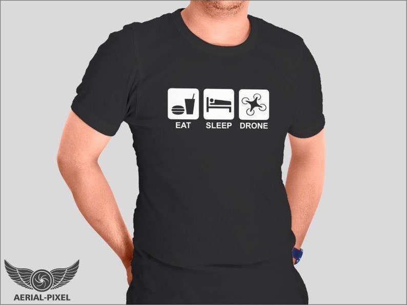 May include: Black t-shirt with white text and icons. The text reads "Eat Sleep Drone". The icons depict a drink, a bed, and a drone.