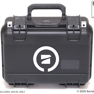 May include: Black hard case with a white logo and handle. The case has a rectangular shape with rounded corners and secure latches. The logo is a white circle with a stylized design inside. Text on the case reads "DECALS, APPAREL, 3D PRINTS".